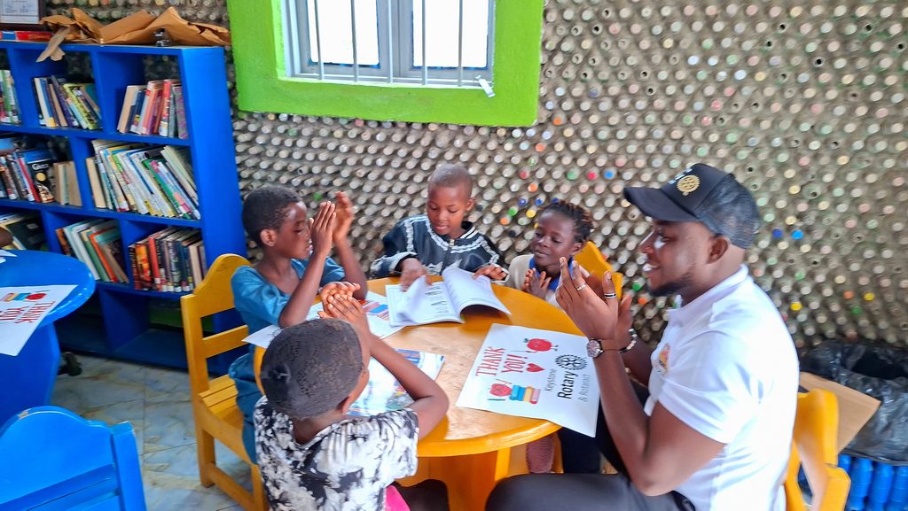 Rotaract Club member, Paschal, reading story books with kids from the refugee settlement